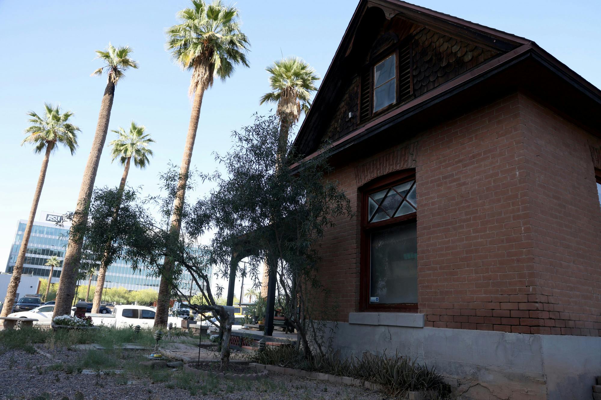 The Louis Emerson House, a 1902 brick Queen Anne in downtown Phoenix, photographed from the side with modern downtown buildings in the background
